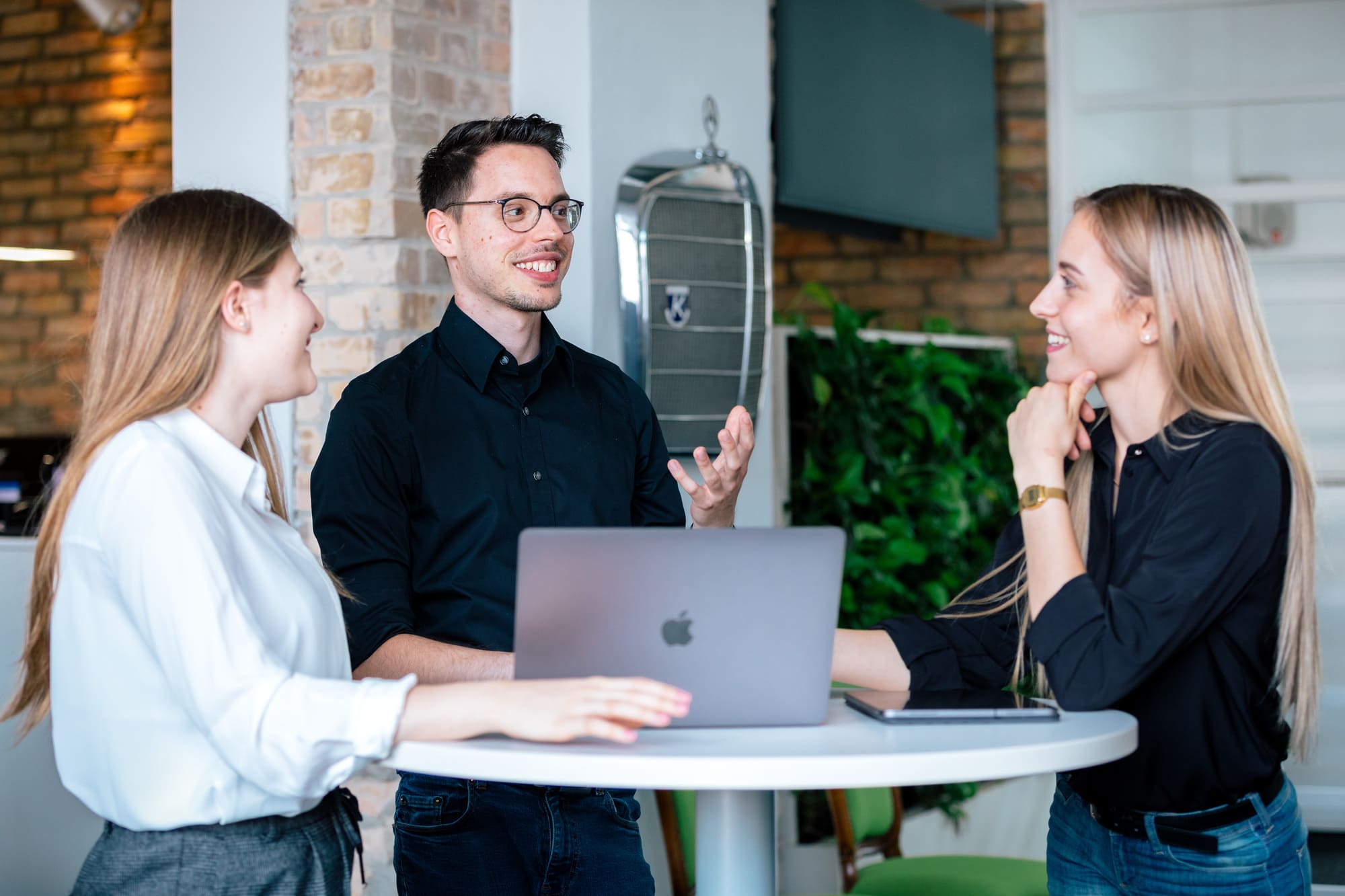 Mitarbeiter Unterhalten sich gestikulierend an einem runden Stehtisch.