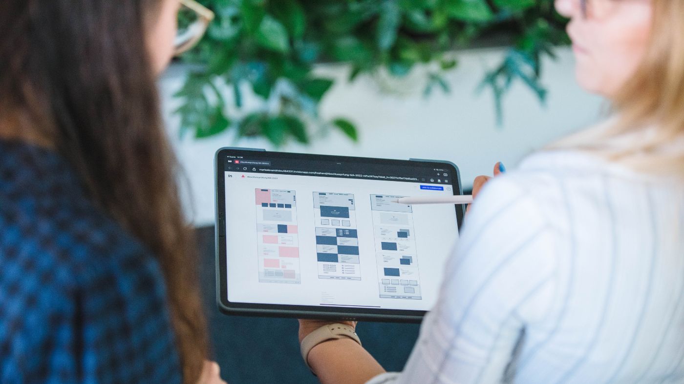 Core Web Vitals: So machen Sie Ihre WordPress-Website fit für Google Zwei Personen schauen gemeinsam auf ein Tablet und unterhalten sich.