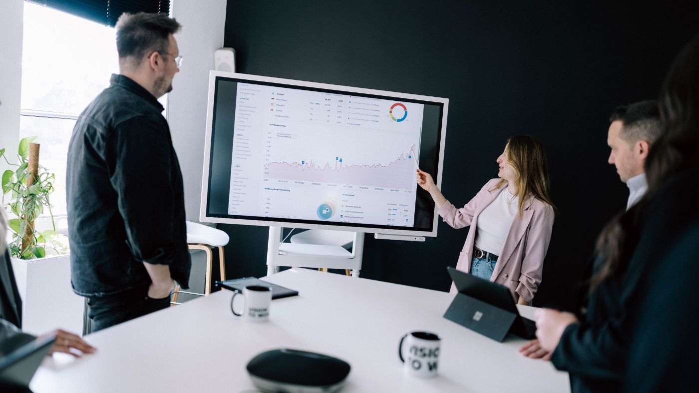 Relaunch Kompetenz Eine Frau steht vor einem Whiteboard und präsentiert eine analytik Grafik